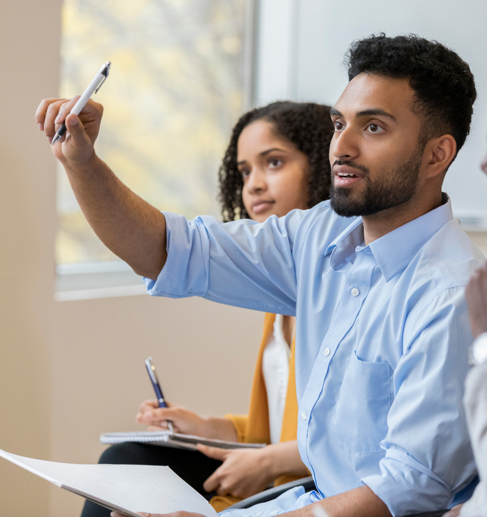 A businessman raises his hand to ask a question in a training session